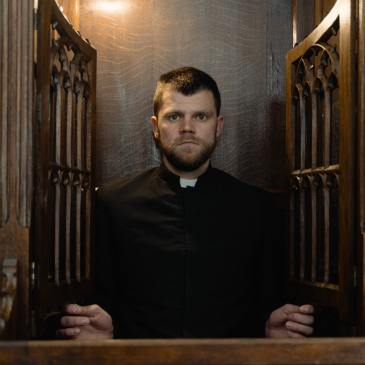 A Catholic priest looking out from the confessional booth